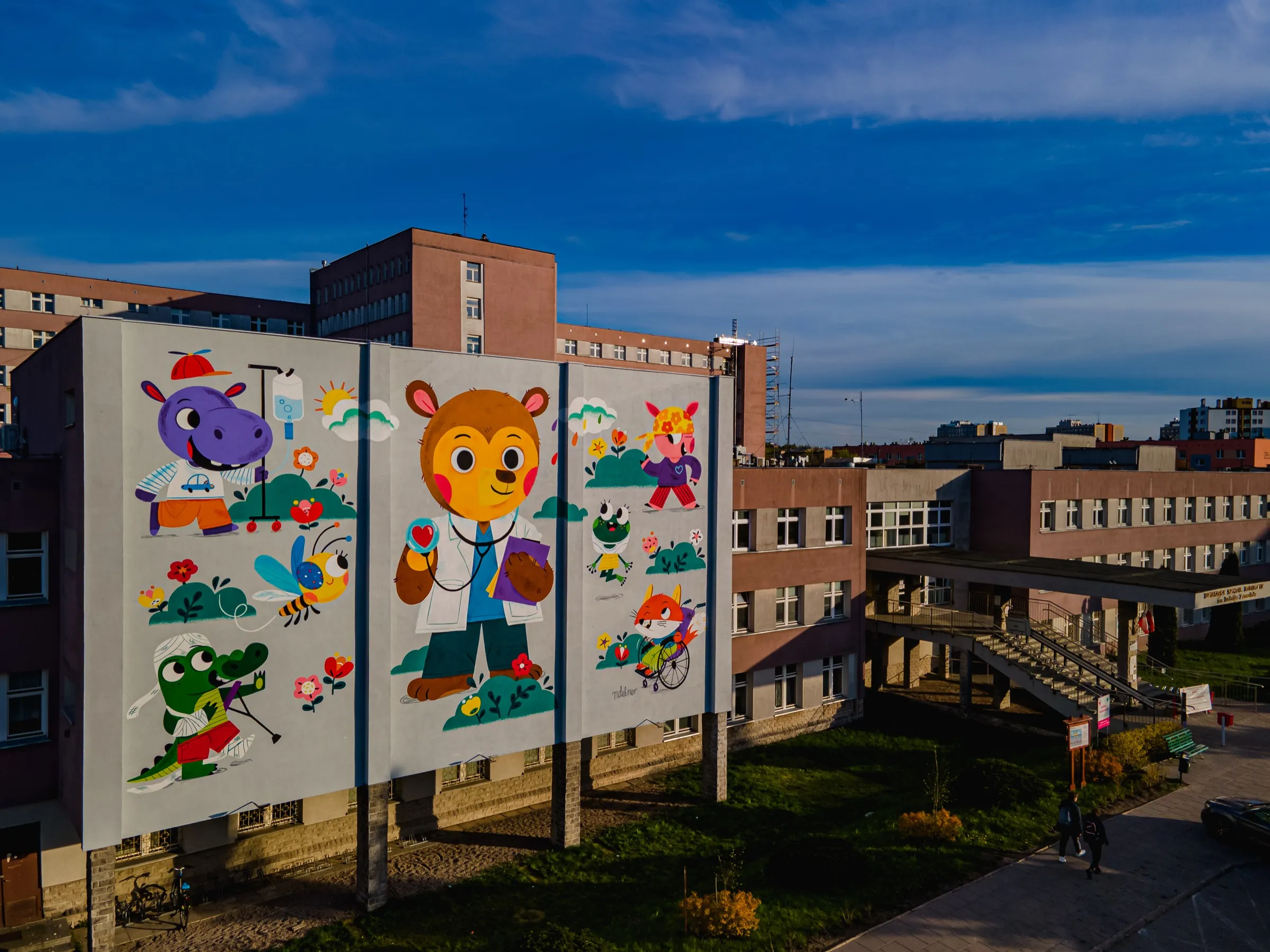 Drone view of the front wall of the children’s hospital in Białystok with a mural: a bear doctor with a stethoscope, a hippo, a crocodile on crutches, a bee and a fox in a wheelchair
